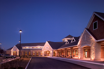 The front of the Lodge at Des Peres, illuminated by lights, featuring a spacious driveway leading to its entrance.