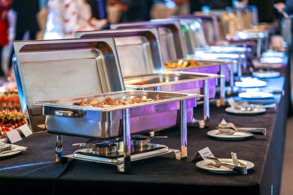A long line of food trays neatly arranged on a table, showcasing a variety of dishes ready for serving.
